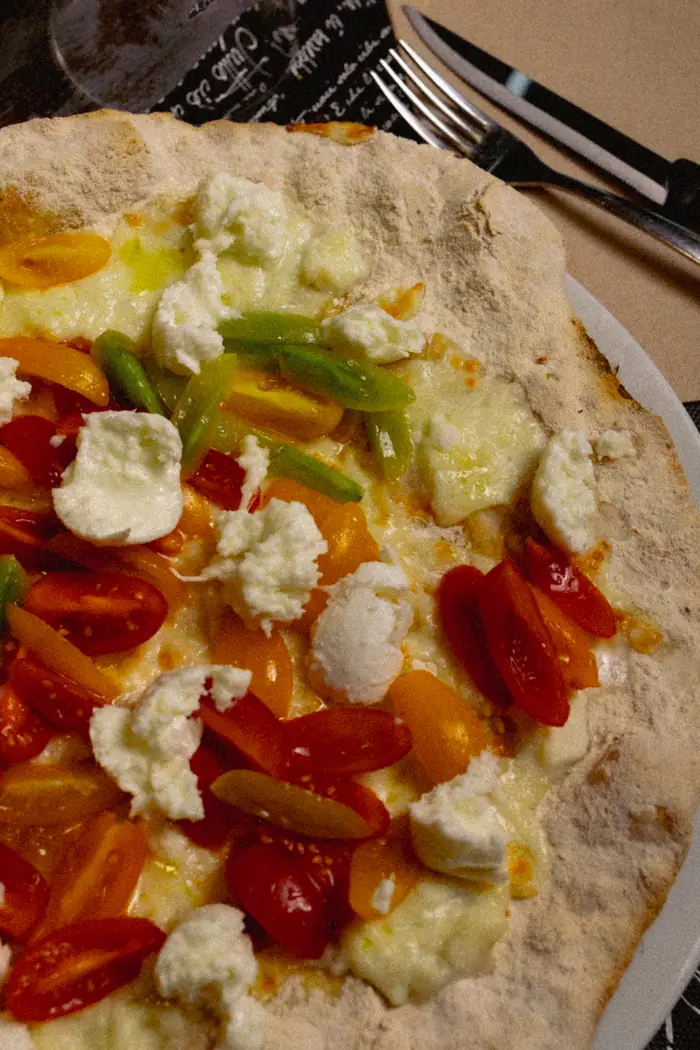 Pizza sottile con datterini gialli e rossi, zucchine e burrata, vista dall'alto
